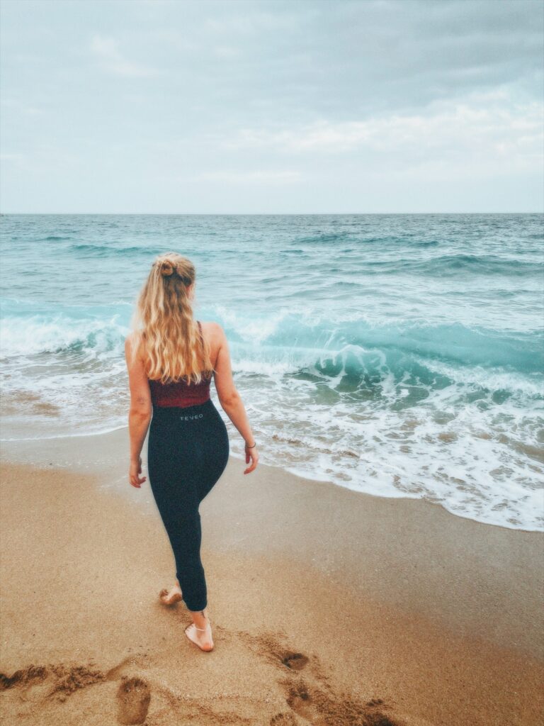 Ein Mädchen steht am Strand vor hohen Wellen